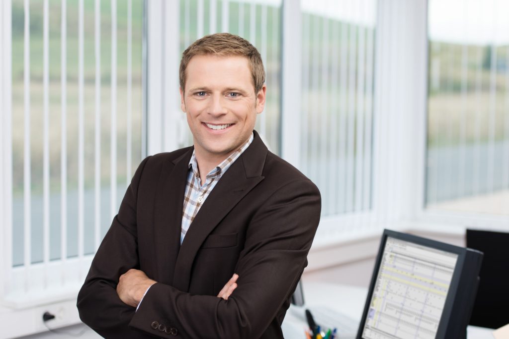 Businessman leadning on a desk with arms crossed